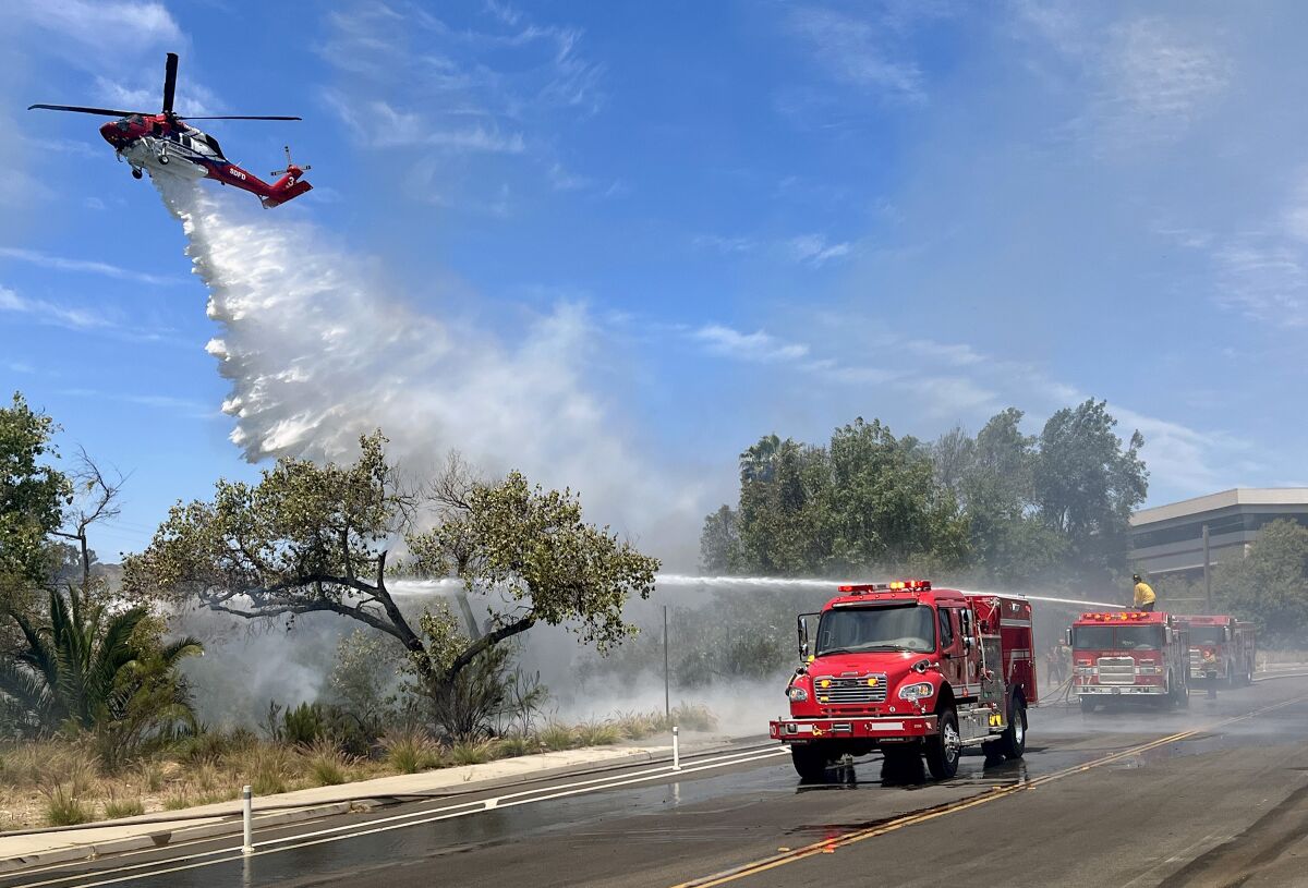 Firefighters work to extinguish a brush fire on San Diego Mission Road, west of Fairmount Avenue on Tuesday.