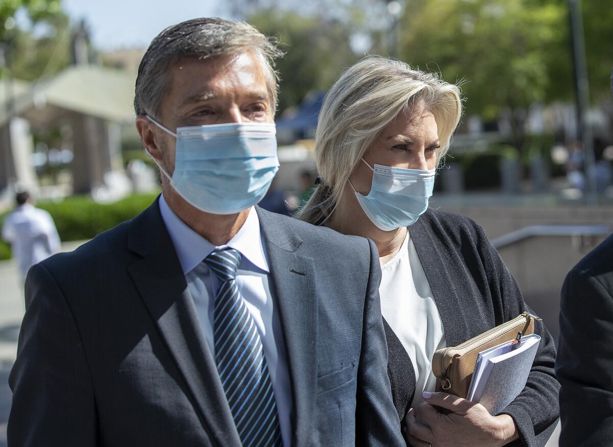 A man and a woman in blue face masks outdoors.