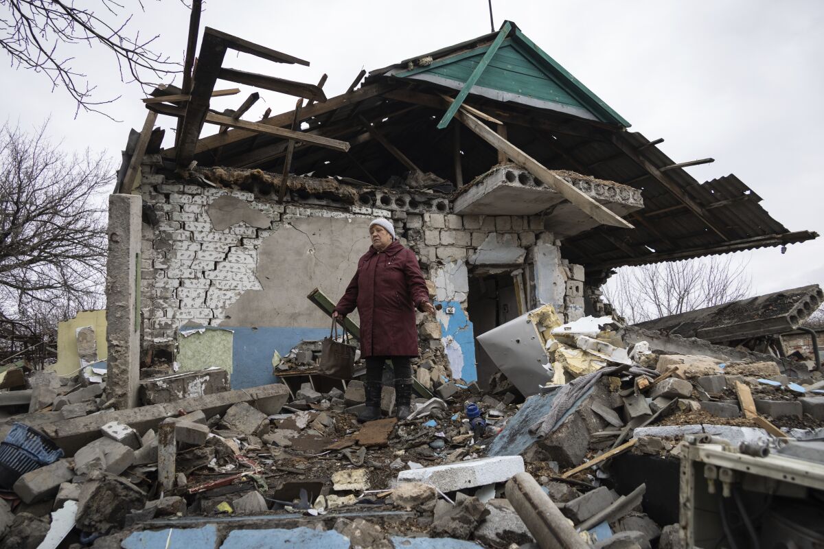 A woman weeps, standing in the debris of her house in Ukraine, which was struck by a mortar shell 