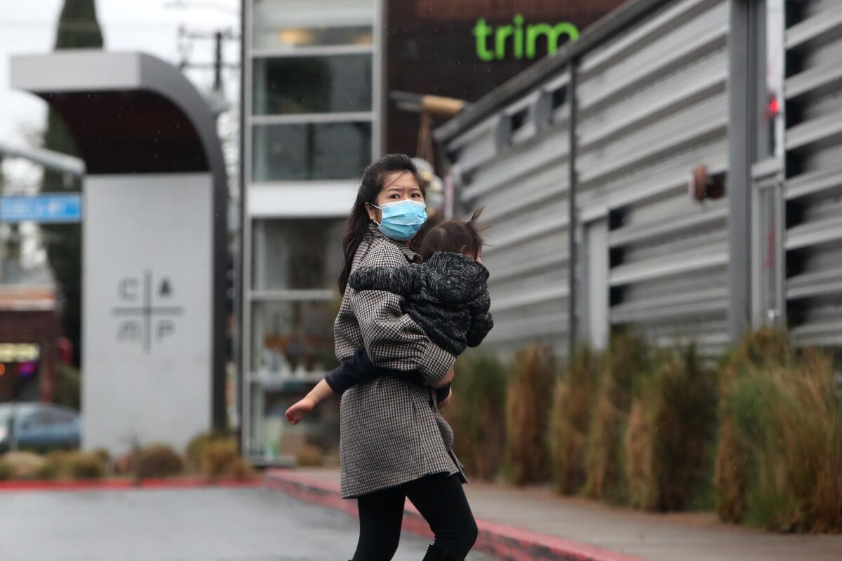 A woman carries her child at The Camp on Tuesday in Costa Mesa. 