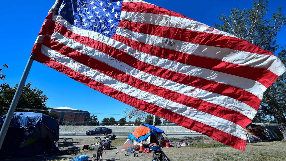 The U.S. flag flies near a homeless person's tent at an encampment beside the Santa Ana River in Anaheim on Feb. 20.