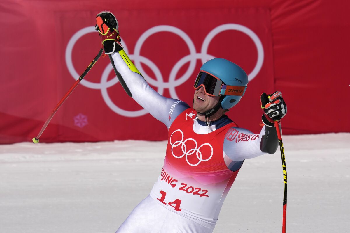 Ryan Cochran-Siegle smiles and raises his arms after skiing at the 2022 Olympics.