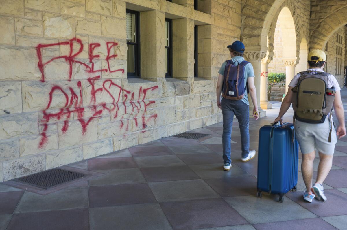 Students walk by Free Palestine graffiti on a campus building