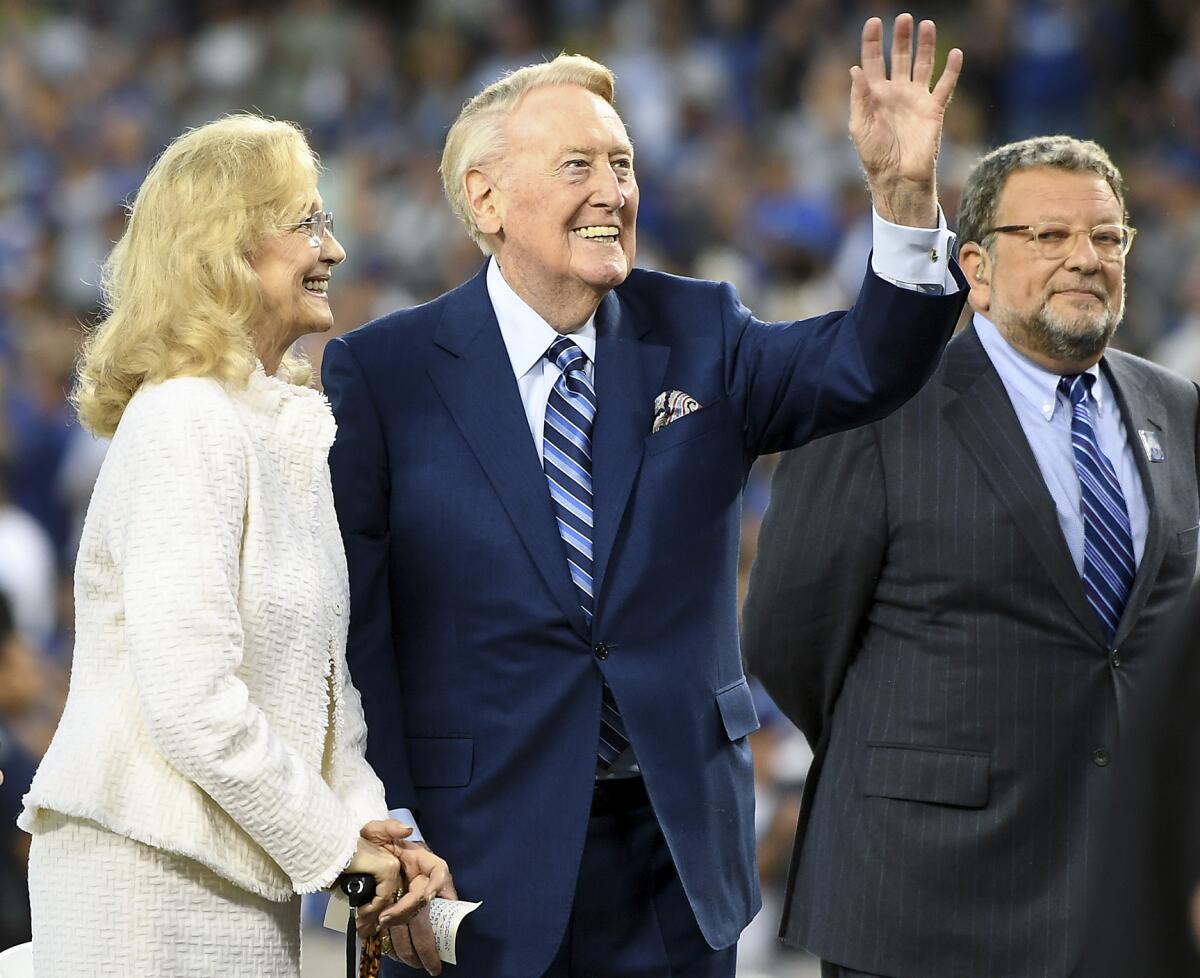 Dodgers announcer Vin Scully, center, waves to the crowd as Charley Steiner, right, looks on before a game on Sept. 20, 2016.