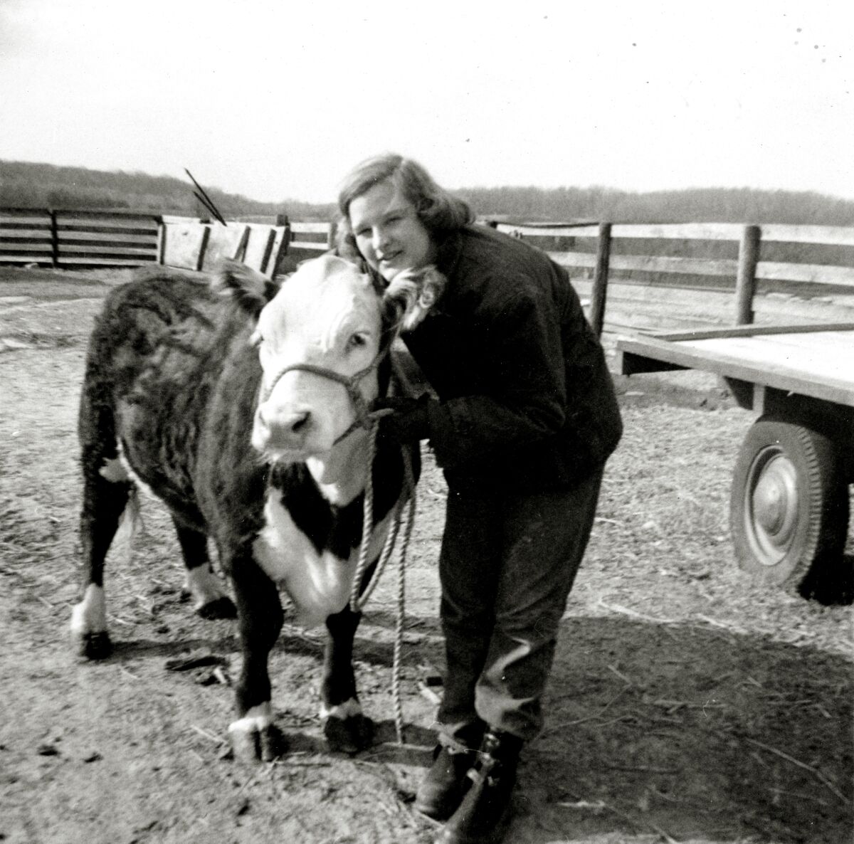 A black and white photo of a girl with short hair posing with her ox.