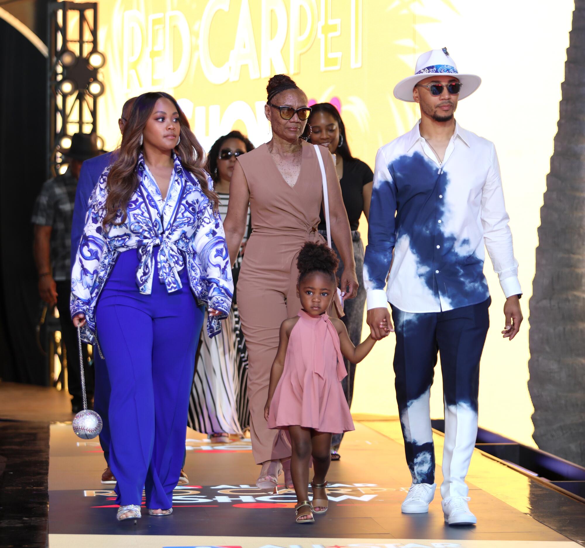 Mookie Betts arrives in a blue and white tie dye outfit with his family at the red carpet show.