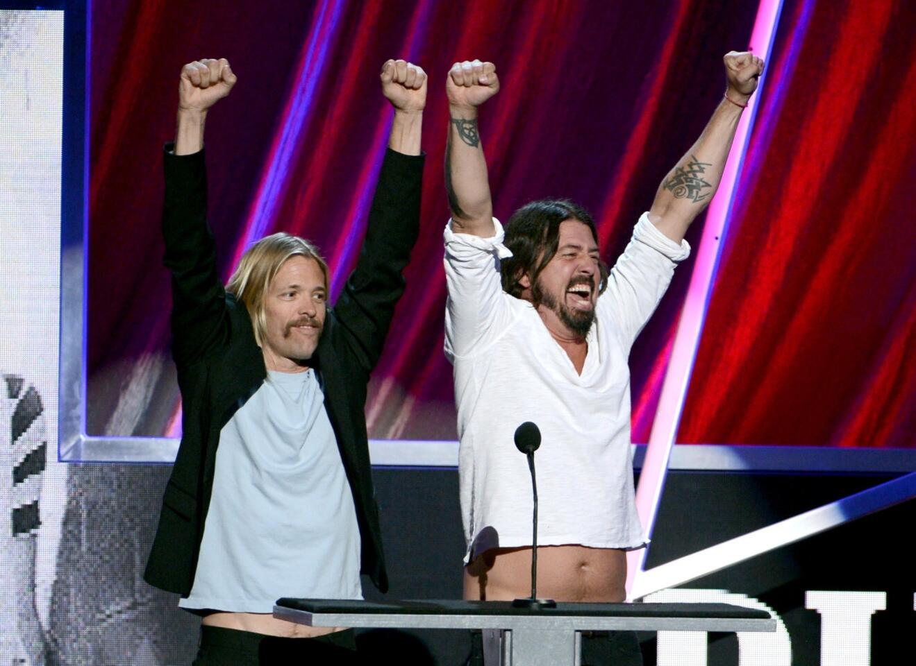 Presenters Taylor Hawkins and Dave Grohl of Foo Fighters, displaying their musical enthusiasm, speak onstage at the 28th Rock and Roll Hall of Fame induction ceremony at Nokia Theatre L.A. Live.