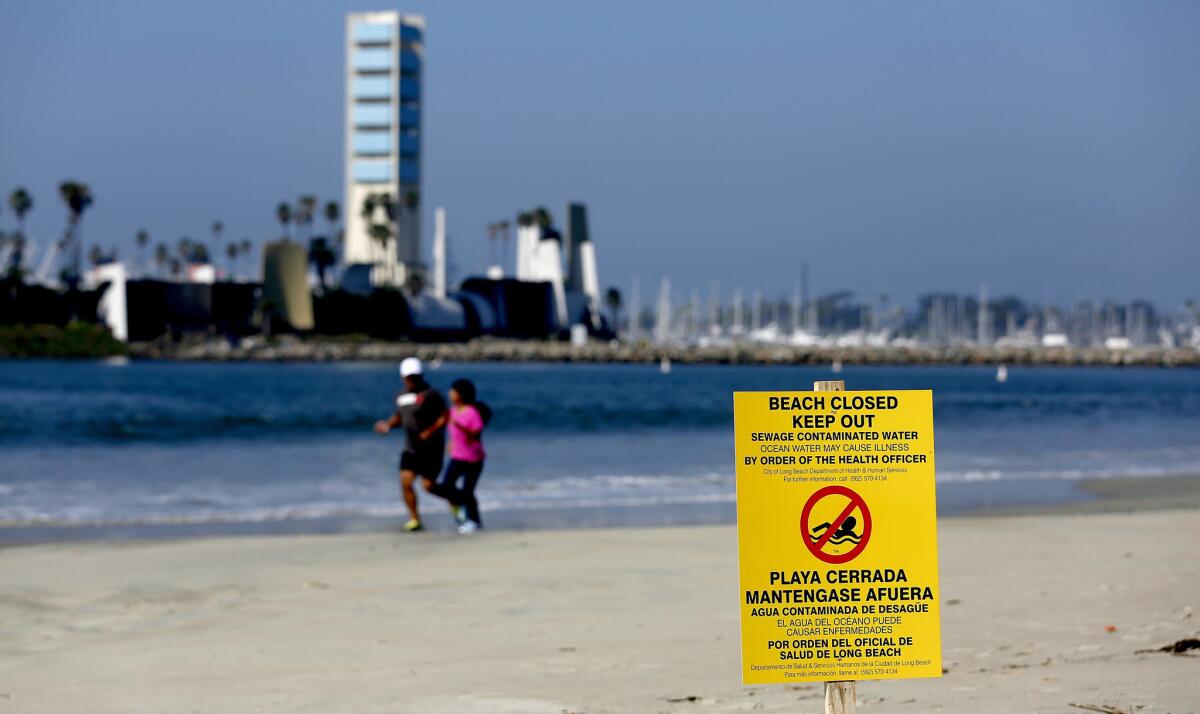 Two people jog along the shoreline in Long Beach on July 19, after officials closed the beach to swimming following a sewage spill.