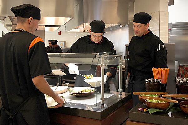 Assistant cooks Jose Espenoza, center, and Moses Mendez, right, work behind the counter to serve up a dish of Thai stir-fried pork with long beans at the renovated dining commons at UCLA's Rieber Hall, which will offer several Asian cuisines. It's part of a trend of colleges nationwide replacing old-style cafeterias with innovative ethnic fare that's more healthful. See full story