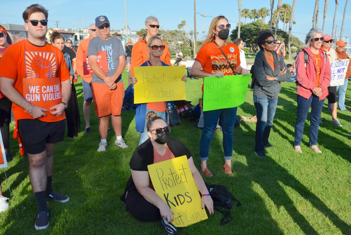 Attendees held signs protesting gun violence during Stop Gun Violence rally at Eisenhower Park in Seal Beach.