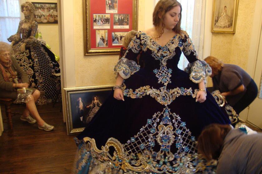 Katie Beckelhymer, a 17-year-old high school senior, is fitted for the gown she will wear at the annual colonial pageant in Laredo, Texas, as her grandmother Anna Haynes, left, looks on.