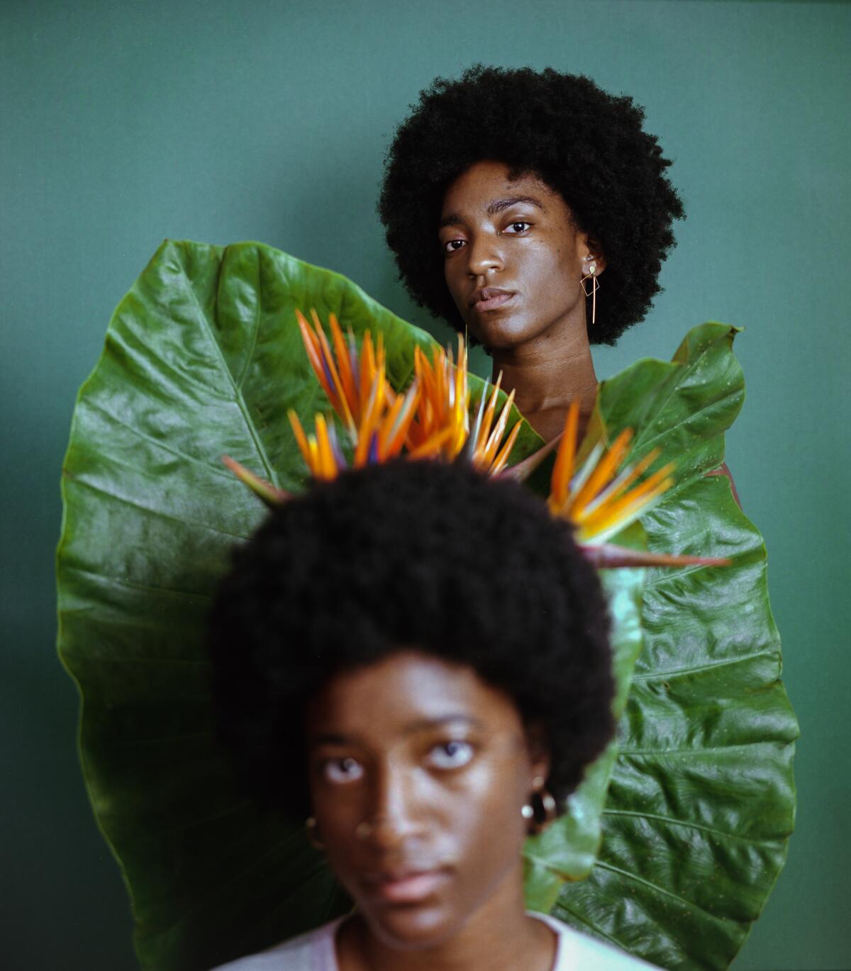 Two subjects pose for a portrait with birds of paradise.