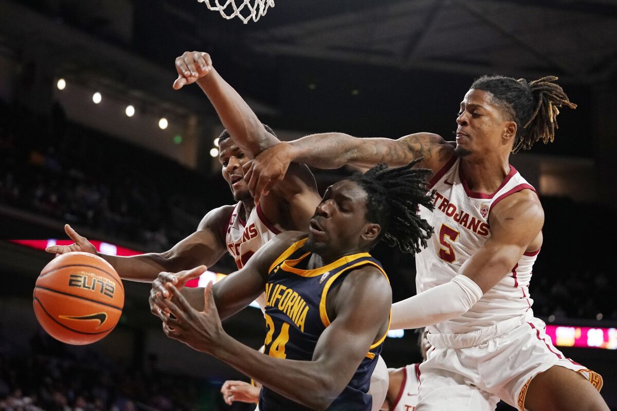 California forward Sam Alajiki, center, tries to shoot as USC guards Ethan Anderson and Isaiah White defend.