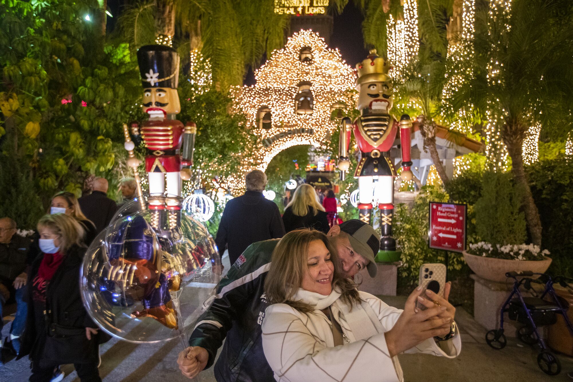 A couple take photos at the Mission Inn Hotel & Spa decorated with lights and big toy nutcracker soldier displays.