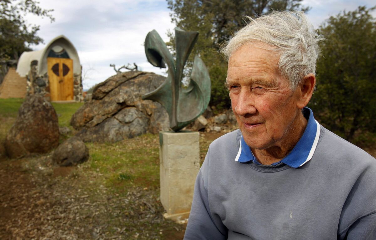 James T. Hubbell has worked in Santa Ysabel since 1958. Behind him are a bronze sculpture and one of many structures on his property.