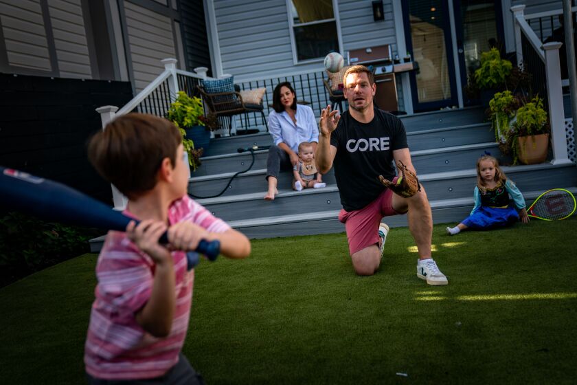 WASHINGTON, DC - AUGUST 23: Rep. Eric Swalwell (D-CA), center, tosses a ball with children Nelson, 5, left, and Kathryn, 3, right, as wife Brittany Watts, and their youngest, Hank, 9 months, look on in the backyard of their home on Tuesday, Aug. 23, 2022 in Washington, DC. Rep. Swalwell has spent the last two years advocating for a compromise to give people a chance to pay their student loan debt back: keep the debt, but forgive the interest. (Kent Nishimura / Los Angeles Times)