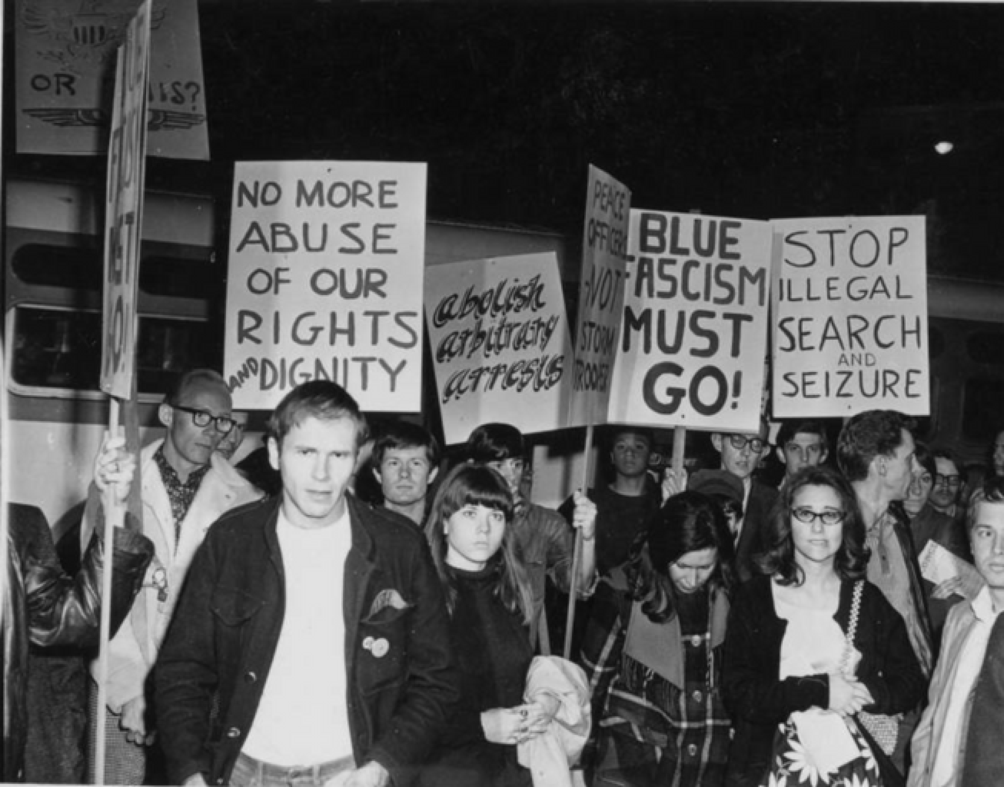 Protesters holding signs with messages including "No more abuse of our rights and dignity" and "Abolish arbitrary arrests."