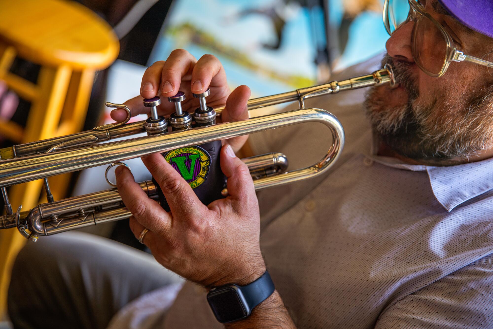 A close-up of a man wearing a watch playing the trumpet.