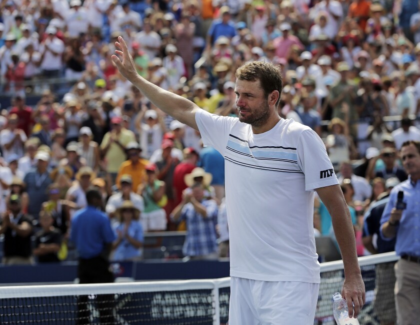 Mardy Fish, carrying a water bottle, waves to the crowd as he walks off the court.