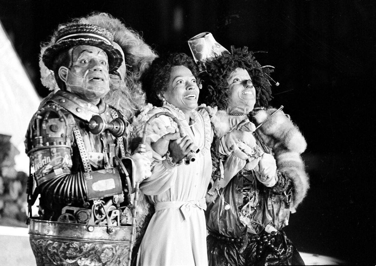 A black and white image of three people performing in a production of "The Wiz." 