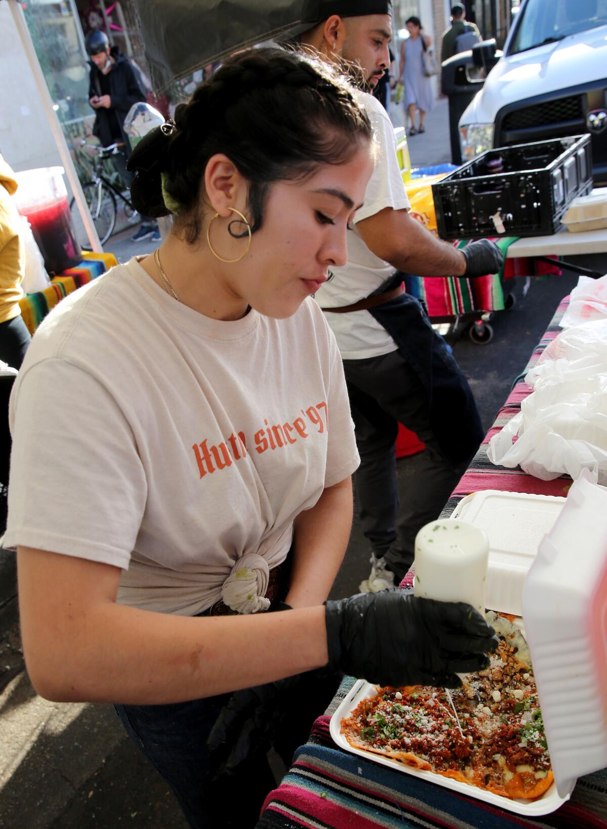 Adriana González completa la preparación de los tacos siguiendo las órdenes de los clientes que llegan a Villa’s Tacos.