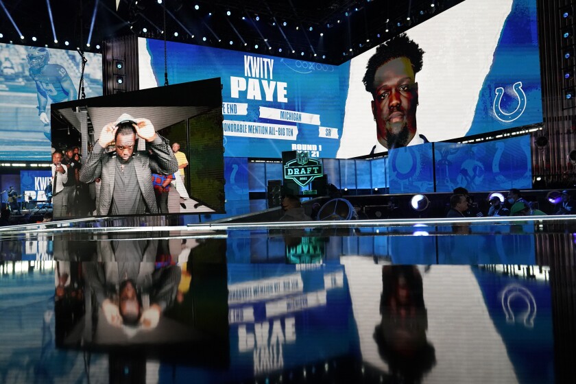 Images of Michigan defensive lineman Kwity Paye are displayed on stage after he was chosen by the Indianapolis Colts with the the 21st pick in the first round of the NFL football draft Thursday April 29, 2021, in Cleveland. (AP Photo/Tony Dejak)