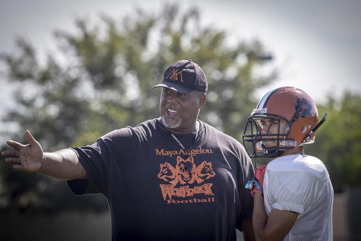 Angelou High football coach Derek Benton works with the team during a practice Tuesday.