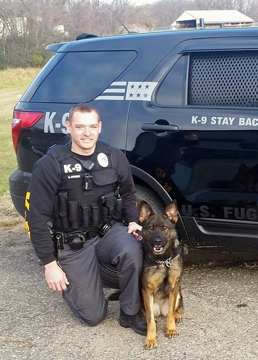This photo provided by the Annandale, Minn., Police Department shows bounty hunter Stew Peters posing for a photo with certified canine Beckah in front of his company vehicle in Annandale, Minn. Some in Minnesota law enforcement cringe at his tactics, apparel and demeanor they fear leaves the impression he is one of them. A new state law passed in May, 2015, with little public airing but aimed mostly at Peters, law forbids bail bondsmen, also known as bounty hunters, from using certain-colored uniforms or vehicles with emblems that the public might mistake for sworn officers. (Annandale Police Department via AP)
