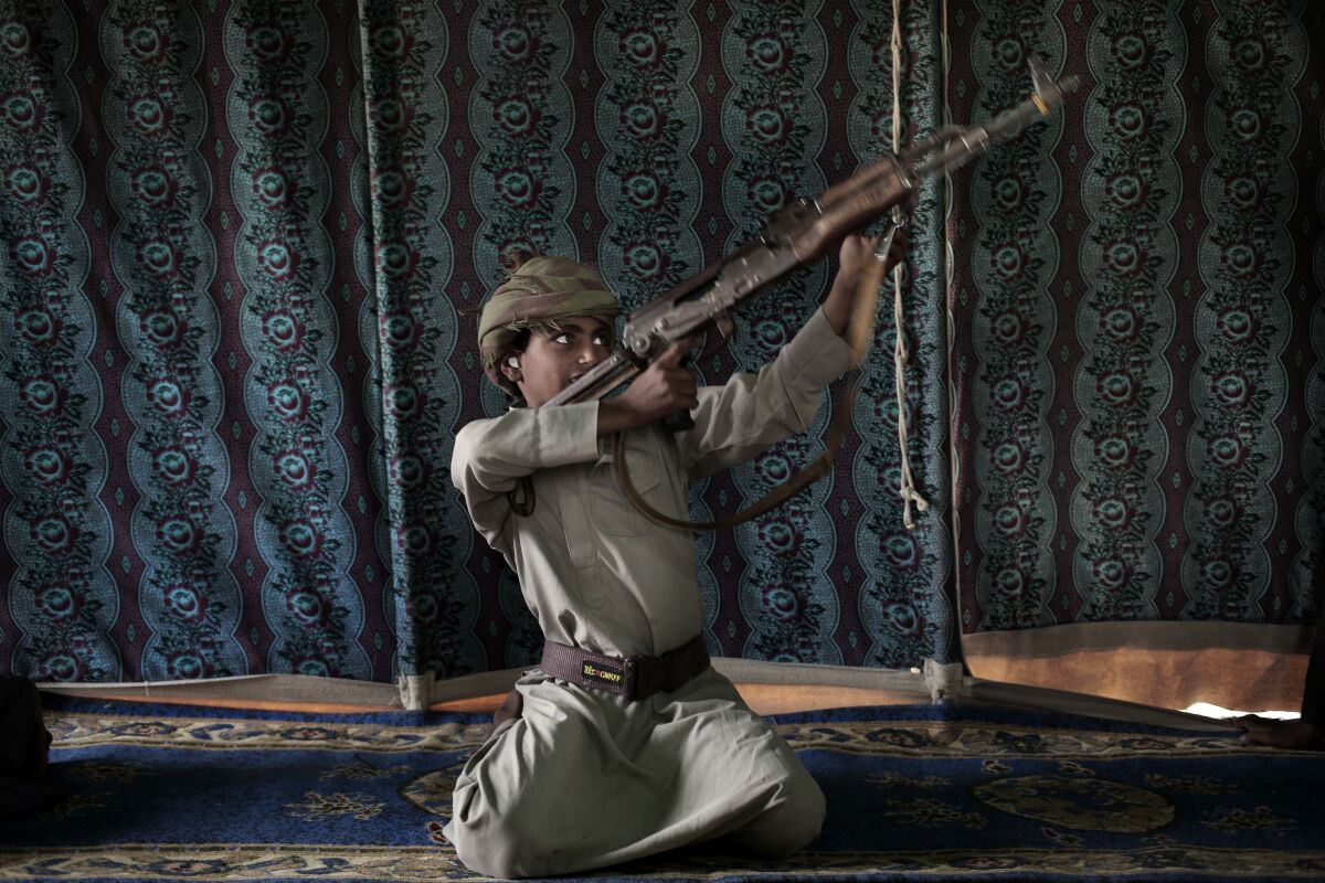 FILE - Kahlan, a 12-year-old former child soldier, demonstrates how to use a weapon, at a camp for displaced persons where he took shelter with his family, in Marib, Yemen, July 27, 2018. emen’s Houthi rebels continue to recruit children into their military ranks to fight in the country’s civil war, despite an agreement with the U.N. in April 2022, to halt the practice. Two Houthi officials acknowledged to the Associated Press that the rebels have recruited several hundred children, some as young as 10, in the past two months. (AP Photo/Nariman El-Mofty, File)
