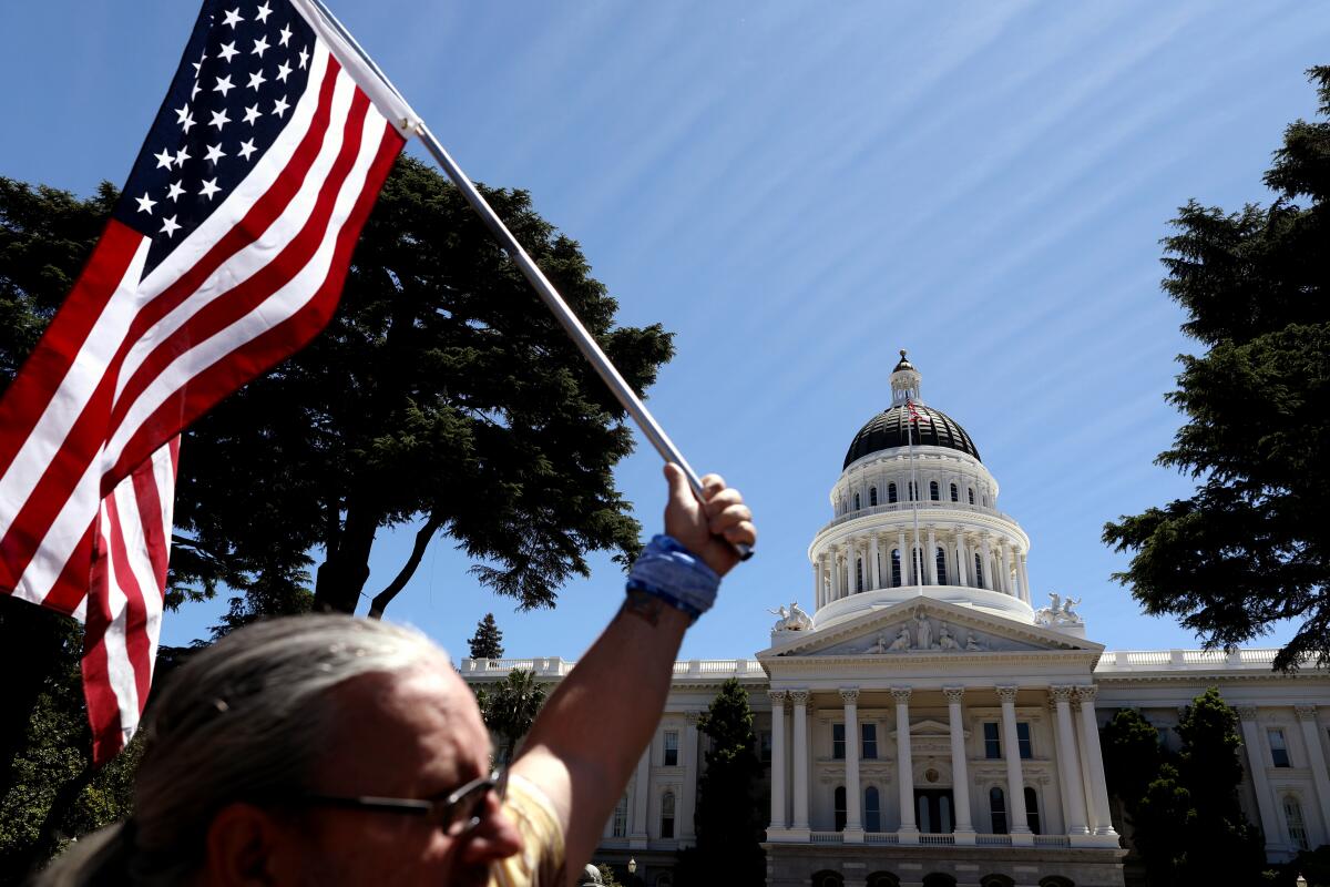 Someone waves an American flag in front of the state capital