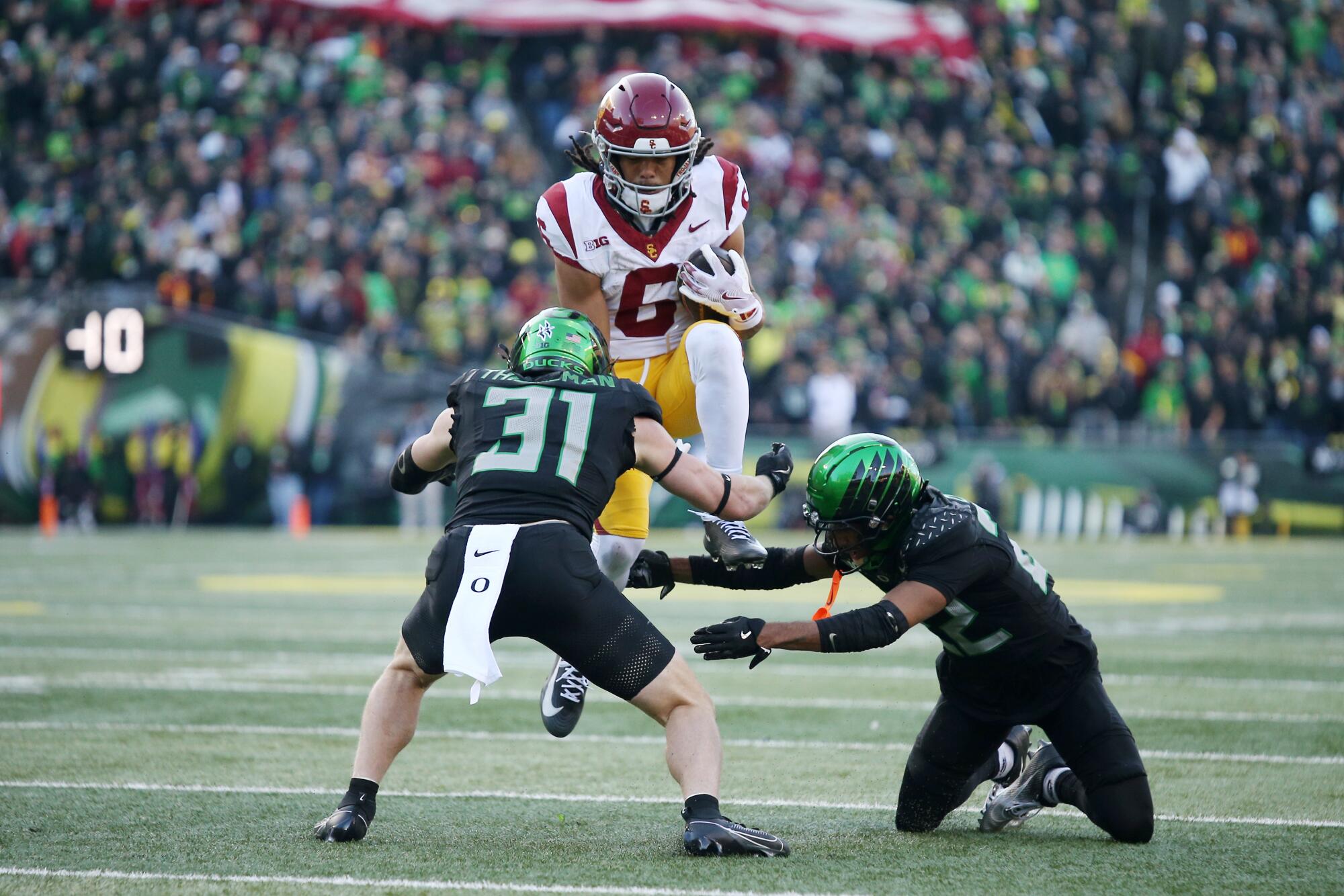 No. 15 USC's Faculty Soccer Playoff hopes shattered in loss to No. 7 Oregon 1 USC wide receiver Makai Lemon attempts to hurdle Oregon defensive backs Dillon Thieneman (31) and Jadon Canady.