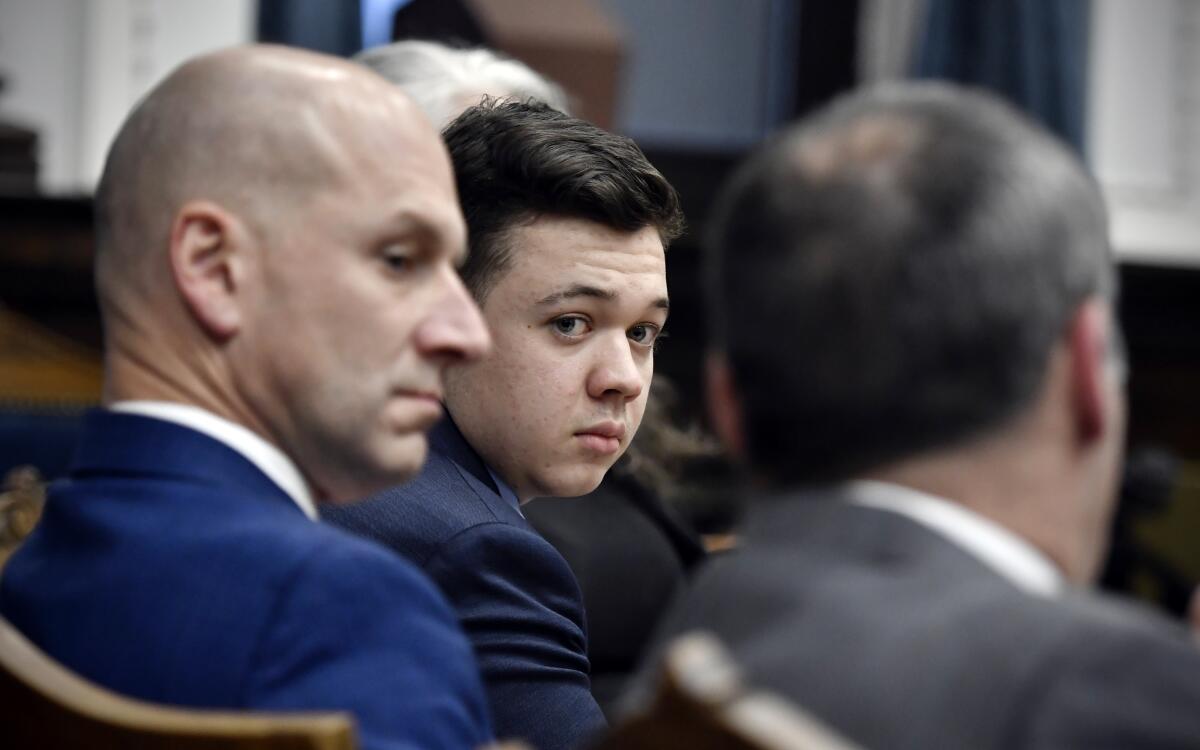 Kyle Rittenhouse, center, looks over to his attorneys in the courtroom.