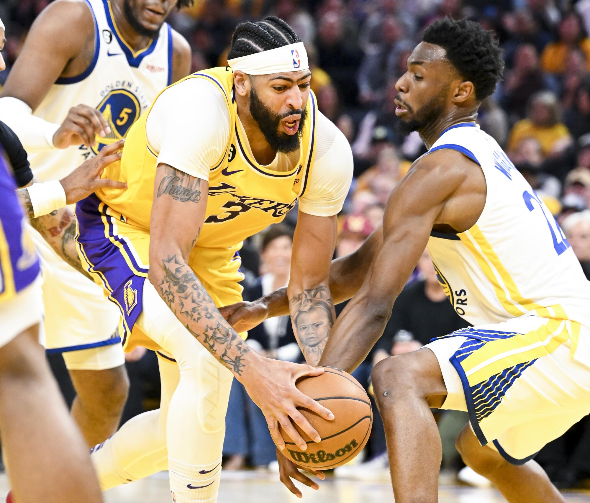 Warriors forward Andrew Wiggins reaches to poke the ball away from Lakers forward Anthony Davis.