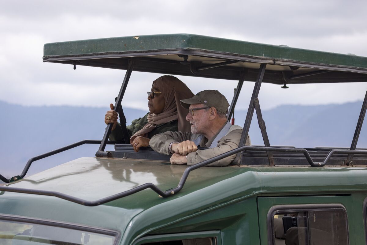 Tanzanian President Samia Suluhu Hassan, left, appears with journalist Peter Greenberg on a safari in Ngorongoro Crater in Tanzania for the television show “The Royal Tour.” Greenberg is resuming the series that shows off the best tourist spots of a country and features the nation’s leader as the tour guide. (Karen Ballard via AP)