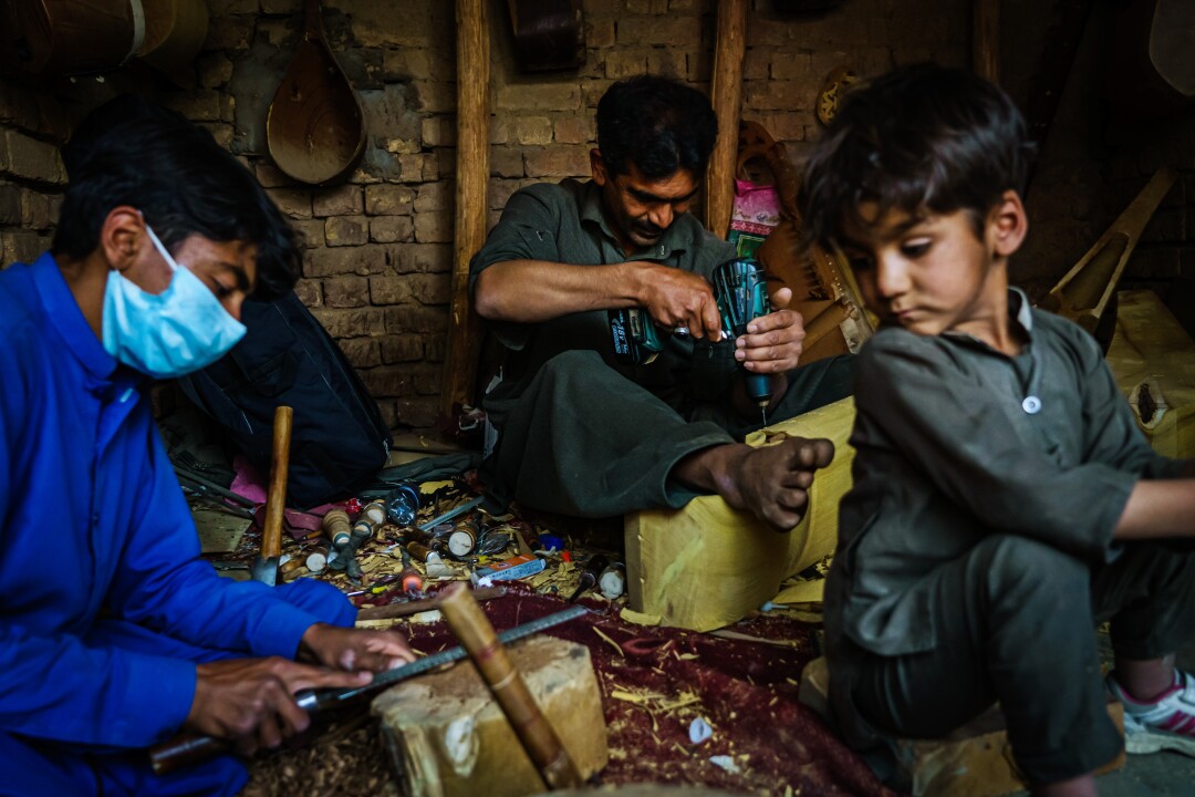 A trio works on musical instrument parts in Kabul