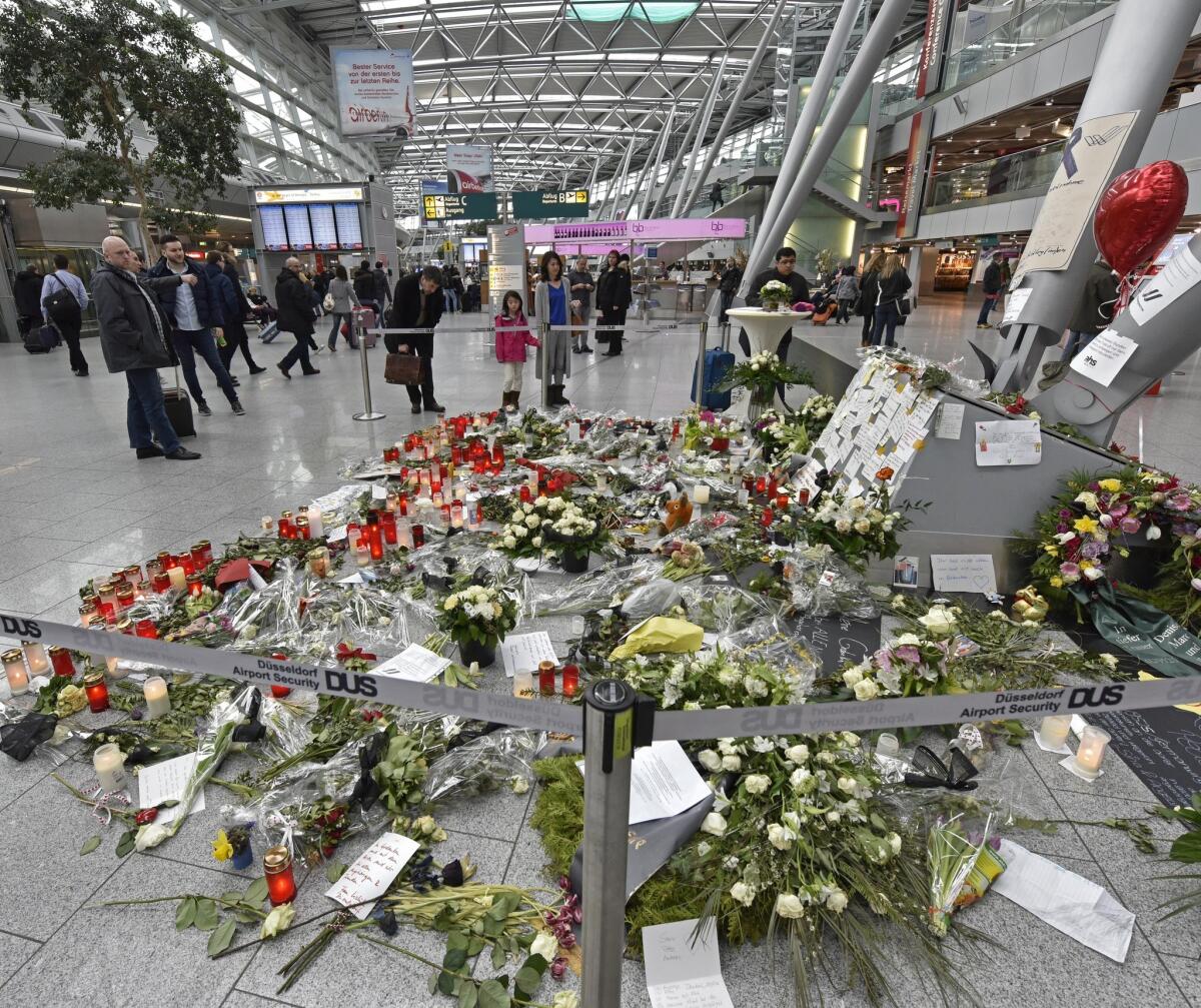 Passengers view the candles and flowers for the victims of the plane crash at the airport in Duesseldorf , Germany, on March 31.