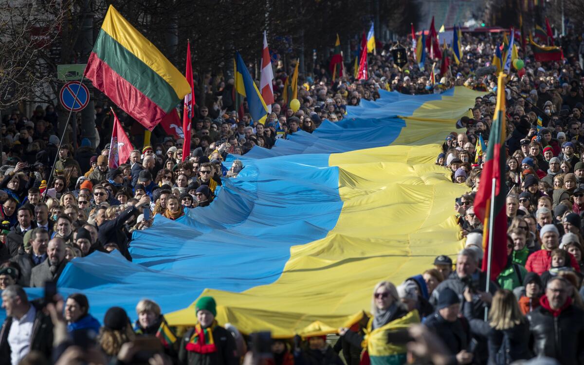 Protesters in Vilnius, Lithuania, carry a giant Ukrainian flag in a demonstration against Russia's attack on Ukraine.