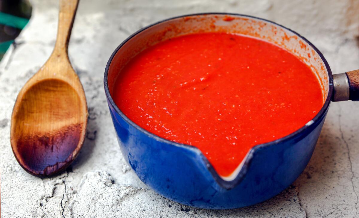  Fresh tomato sauce in a blue saucepan next to a wooden spoon