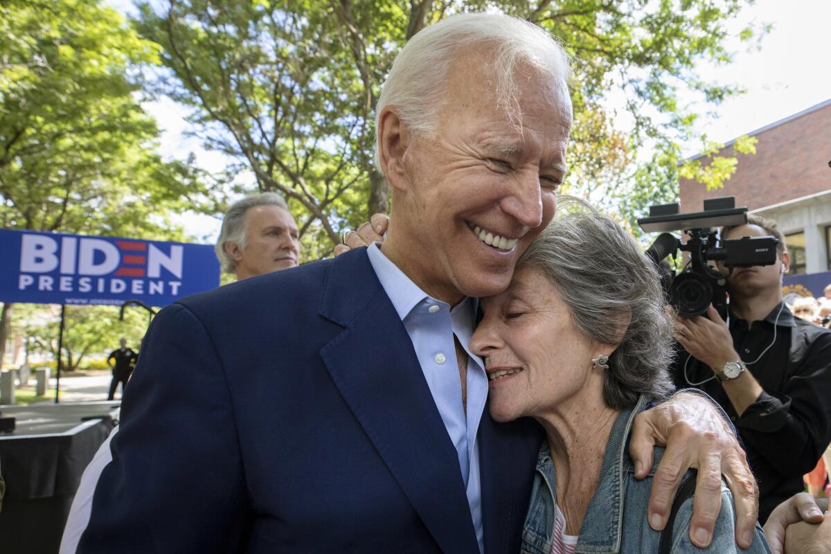 Presidential candidate Joe Biden puts his arm around a supporter.