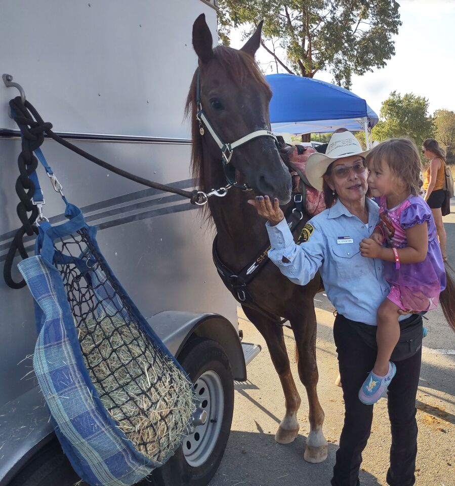 Sheriff’s Department Mounted Patrol volunteer Rosalie Crawford shows off her horse named Riley to attendee Gia Oriol, 3.