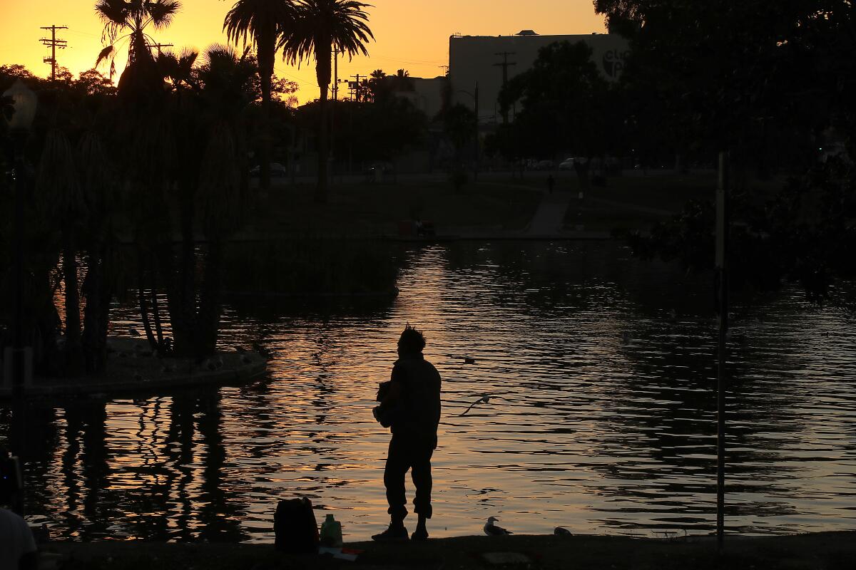 A homeless man collects his belongings before leaving MacArthur Park in Los Angeles on Friday.
