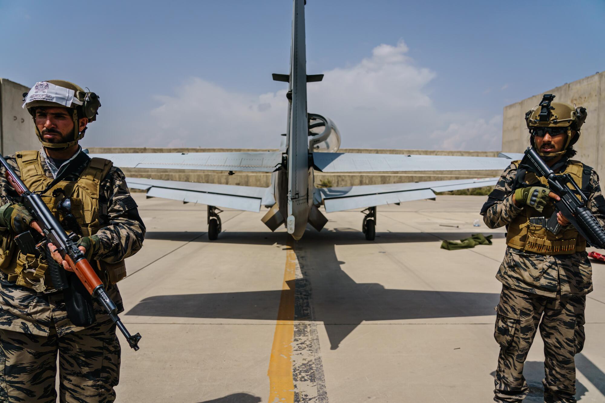 Taliban fighters with guns stand behind an airplane at Hamid Karzai International Airport