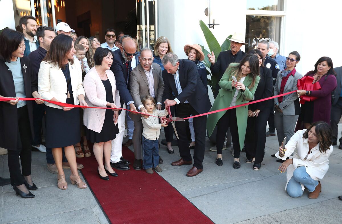 Mo Honarkar with his grandson Truth, 3, cuts a ribbon for the new Hotel Laguna with Mayor Bob Whalen on Tuesday.