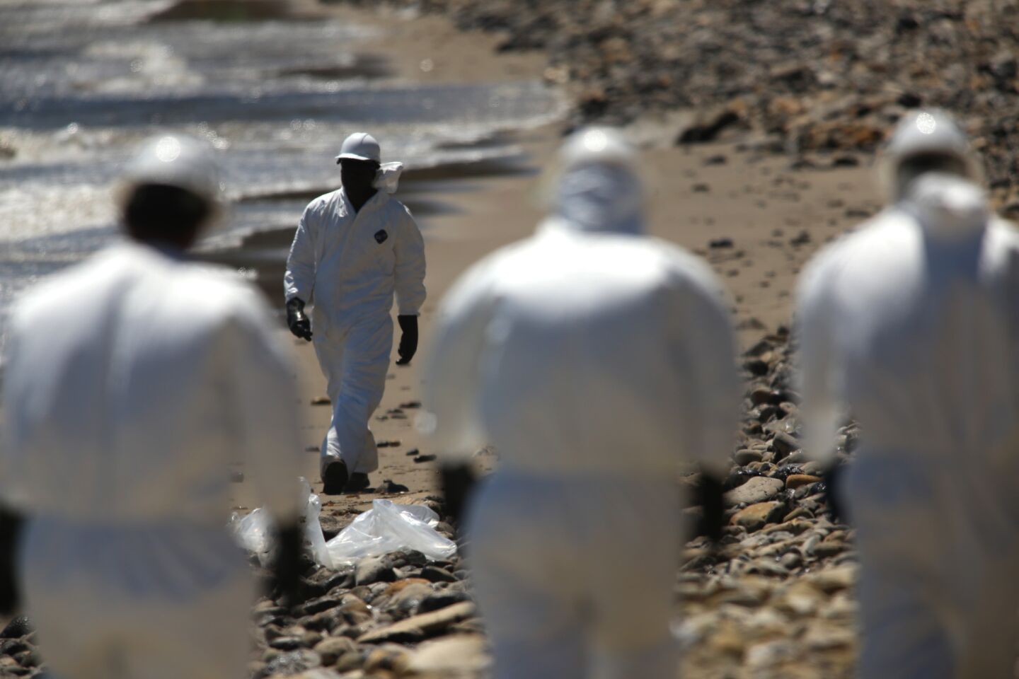 Suited workers continue to clean the shoreline at Refugio State Beach near Santa Barbara.