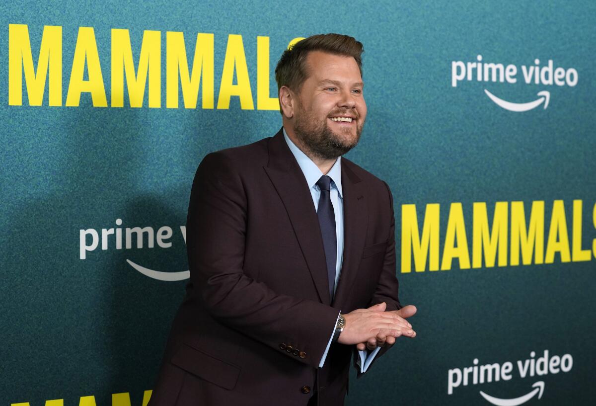 A man wearing a dark suit and rubbing his hands together