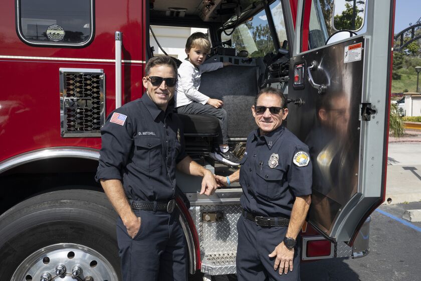 Solana Beach firefighters David Mitchell and Robert Barron show Luka Guiney the fire truck