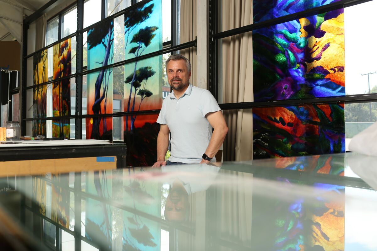 David Judson in front of fused-glass landscapes in his company's studio.