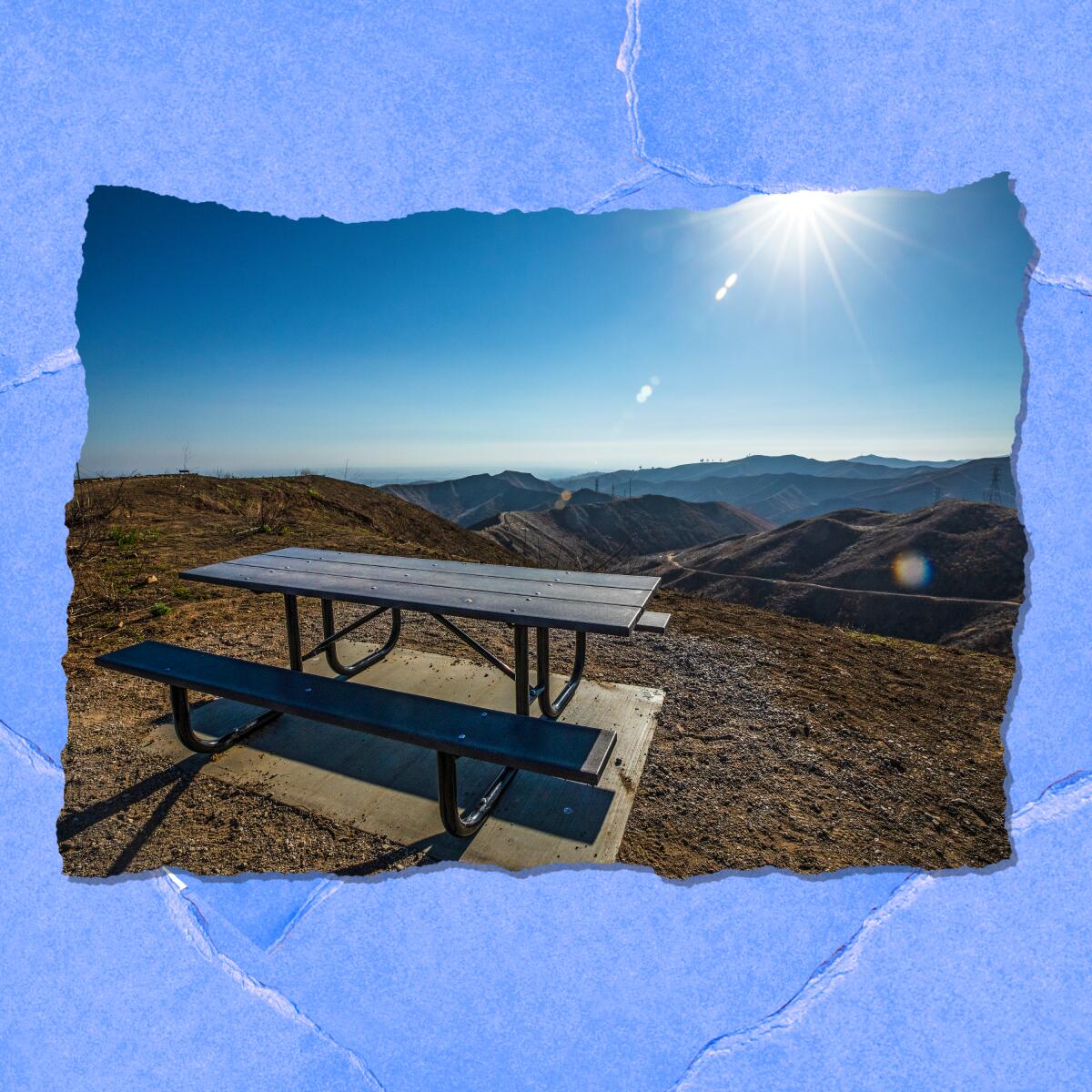The sun shines on an empty picnic table that overlooks barren hills.