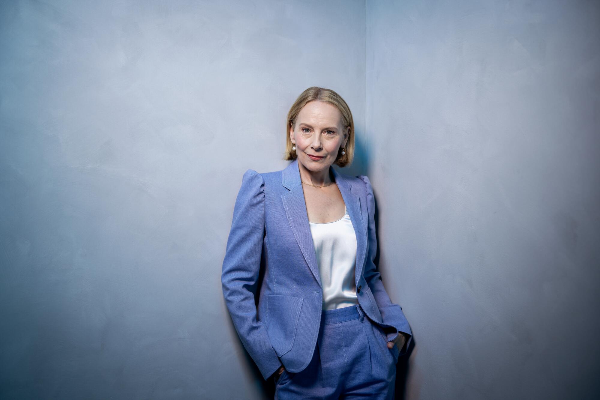 Amy Ryan stands with her hands in the pockets of her pantsuit for a portrait.