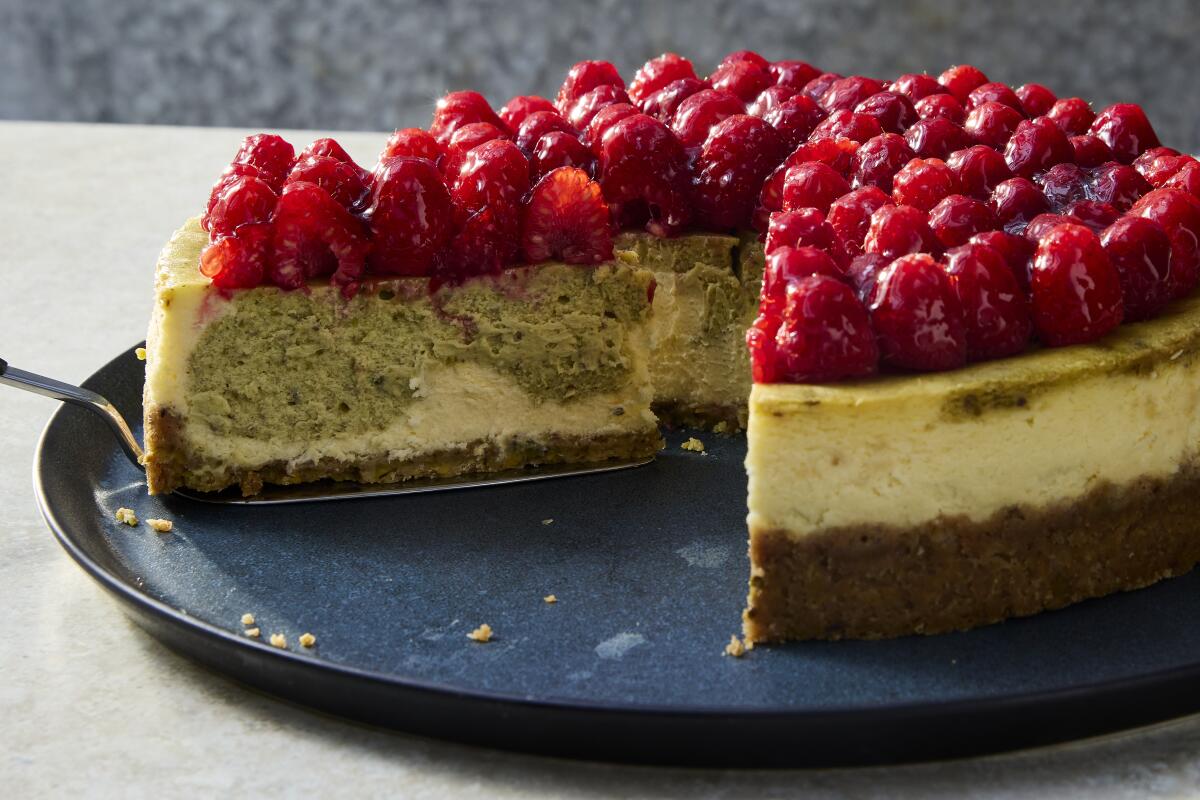 A pistachio cheesecake with raspberry, with a slice being served.